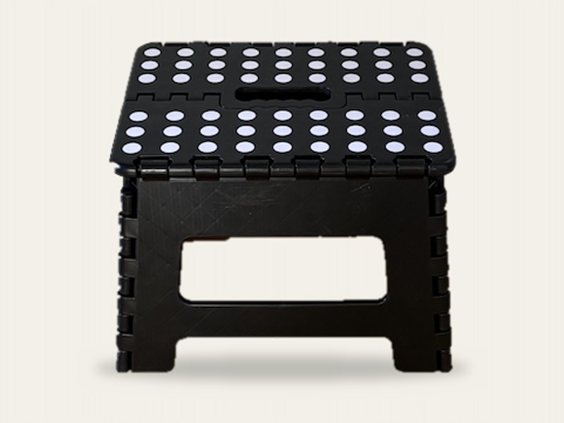 A black folding step stool with white dots on top